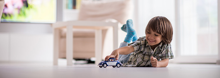 Boy playing with a toy car on the floor.
