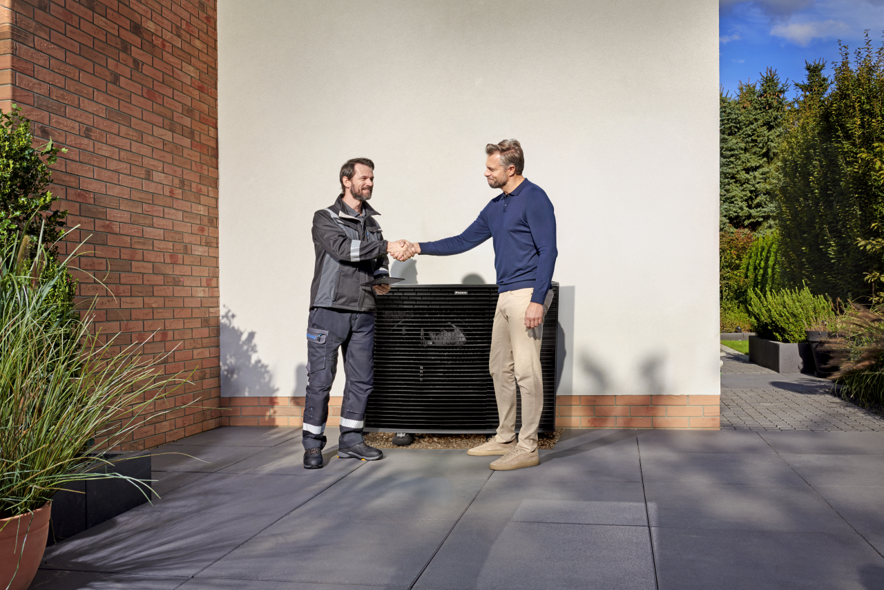 Installer shaking hands with customer in front of a Daikin Altherma outdoor unit