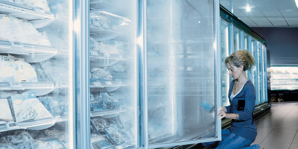 Woman cleaning freezers in a grocery store 